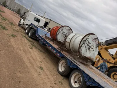 Industrial cable reel being loaded by crane onto a flatbed